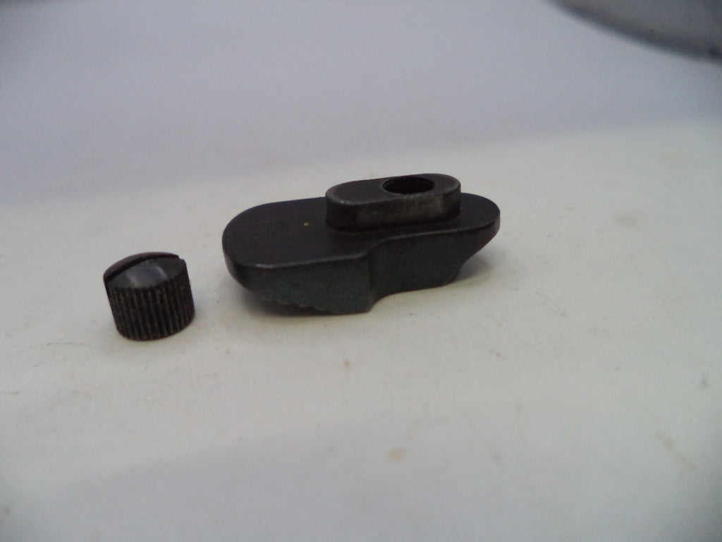 A small black plastic or metal object with a ribbed cylindrical cap-like piece beside it, photographed on a plain light background.