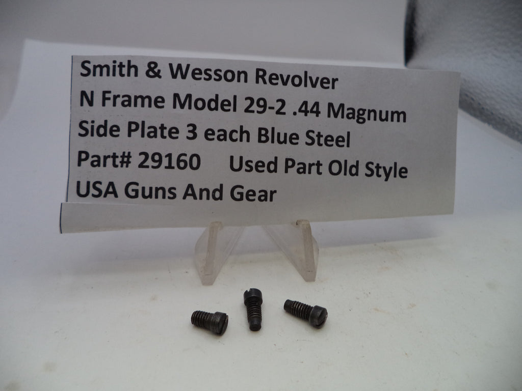 Three small dark metal screws displayed in front of a white sign that reads 'Smith & Wesson Revolver N Frame Model 29-2 .44 Magnum Side Plate 3 each Blue Steel Part# 29160 Used Part Old Style USA Guns And Gear' on a white surface.