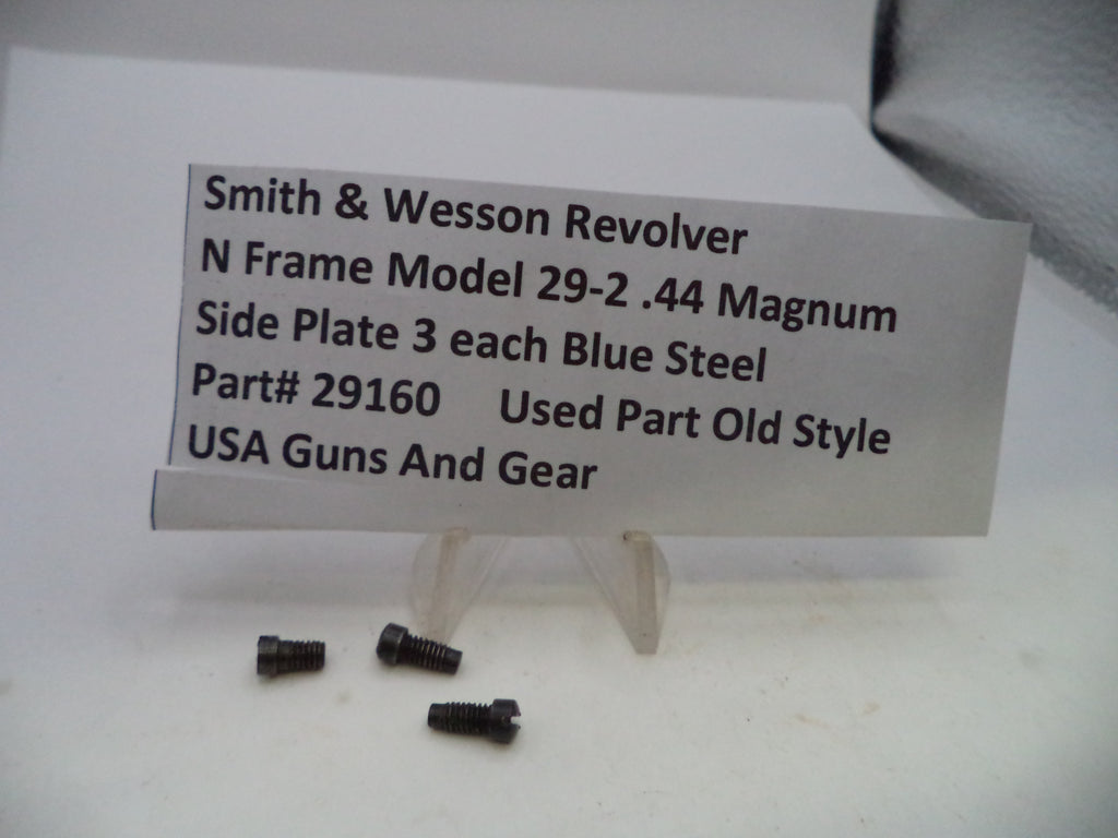 Three small dark metal screws displayed in front of a white sign that reads 'Smith & Wesson Revolver N Frame Model 29-2 .44 Magnum Side Plate 3 each Blue Steel Part# 29160 Used Part Old Style USA Guns And Gear' on a white surface.