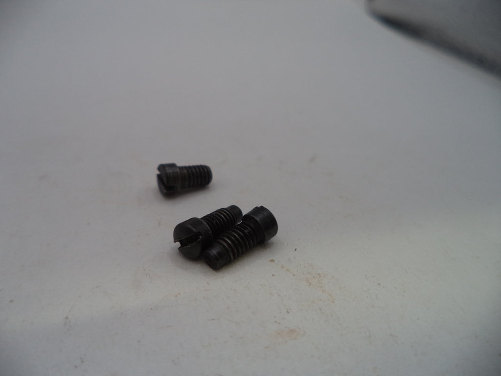 Three small black metal screws with threaded shafts and slotted heads, resting on a light gray surface.