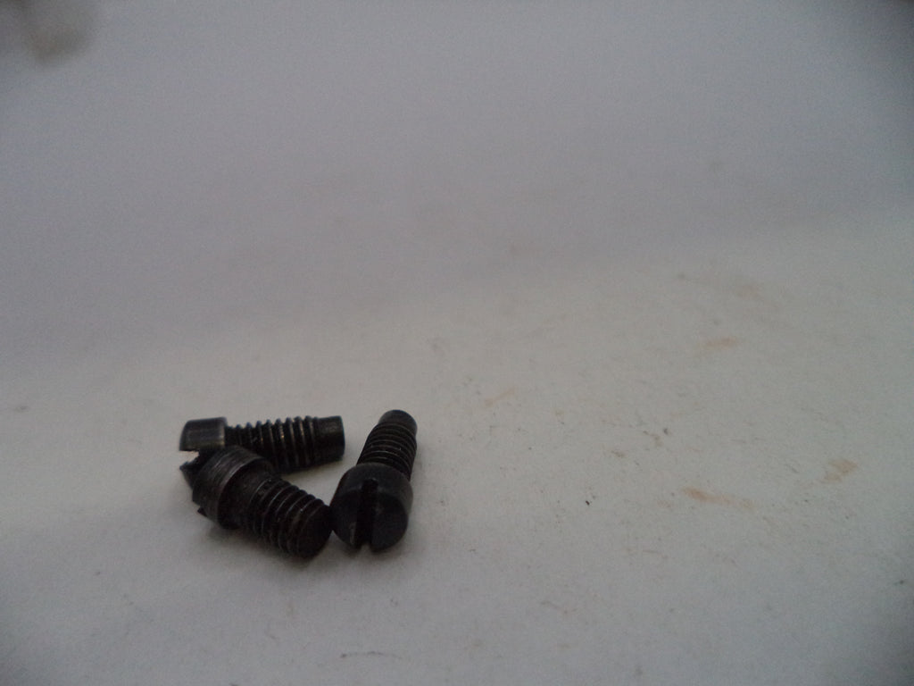 Three small black metal screws with threaded shafts and flat heads, resting on a plain off-white surface.