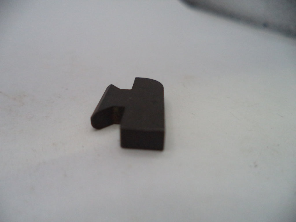 A small dark brown plastic or metal hardware piece with a bent tab, resting on a plain off-white surface.