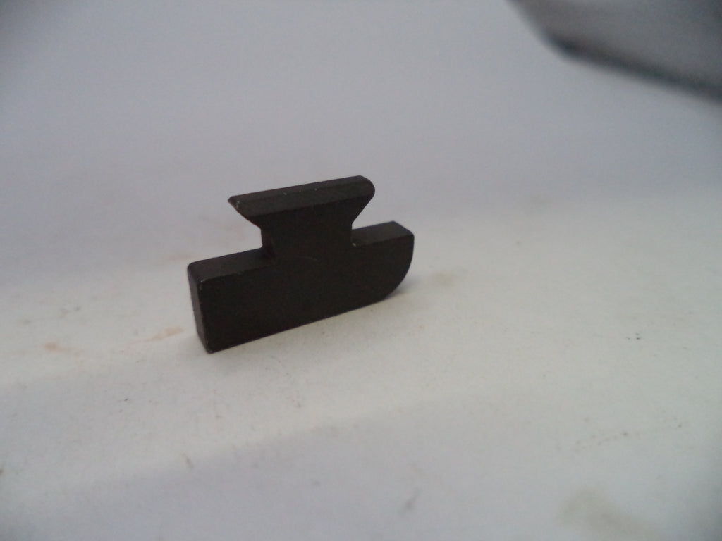 A small dark brown wooden block with a notched top, photographed on a plain off-white surface.