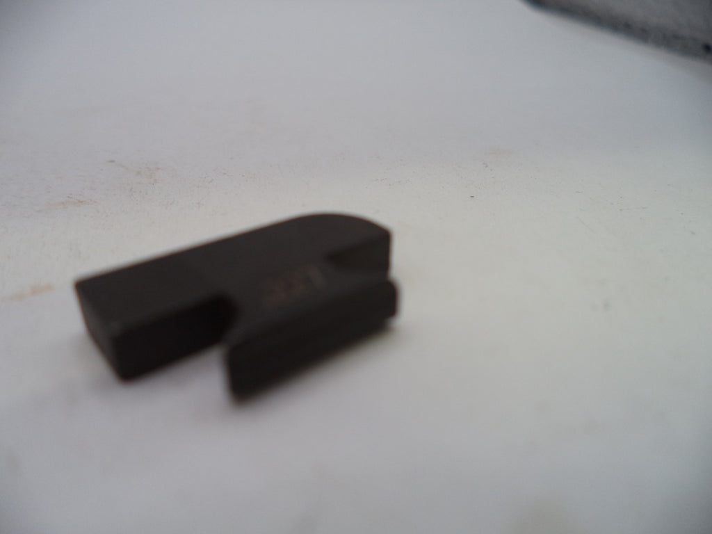 A small black plastic or rubber component with a curved slot, photographed on a plain off-white surface.