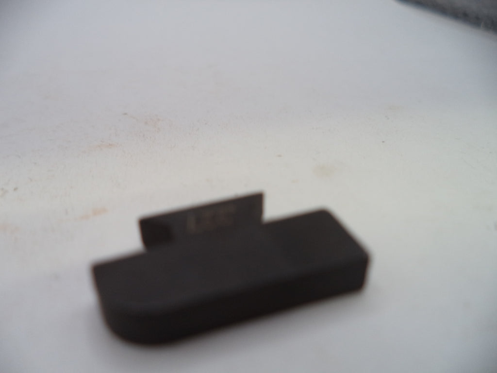 A small black plastic component with a rectangular base and a small tab, photographed on a white surface.