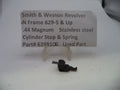 A small black metal cylinder stop and spring part for a Smith & Wesson revolver, displayed on a clear plastic stand in front of a printed label card.
