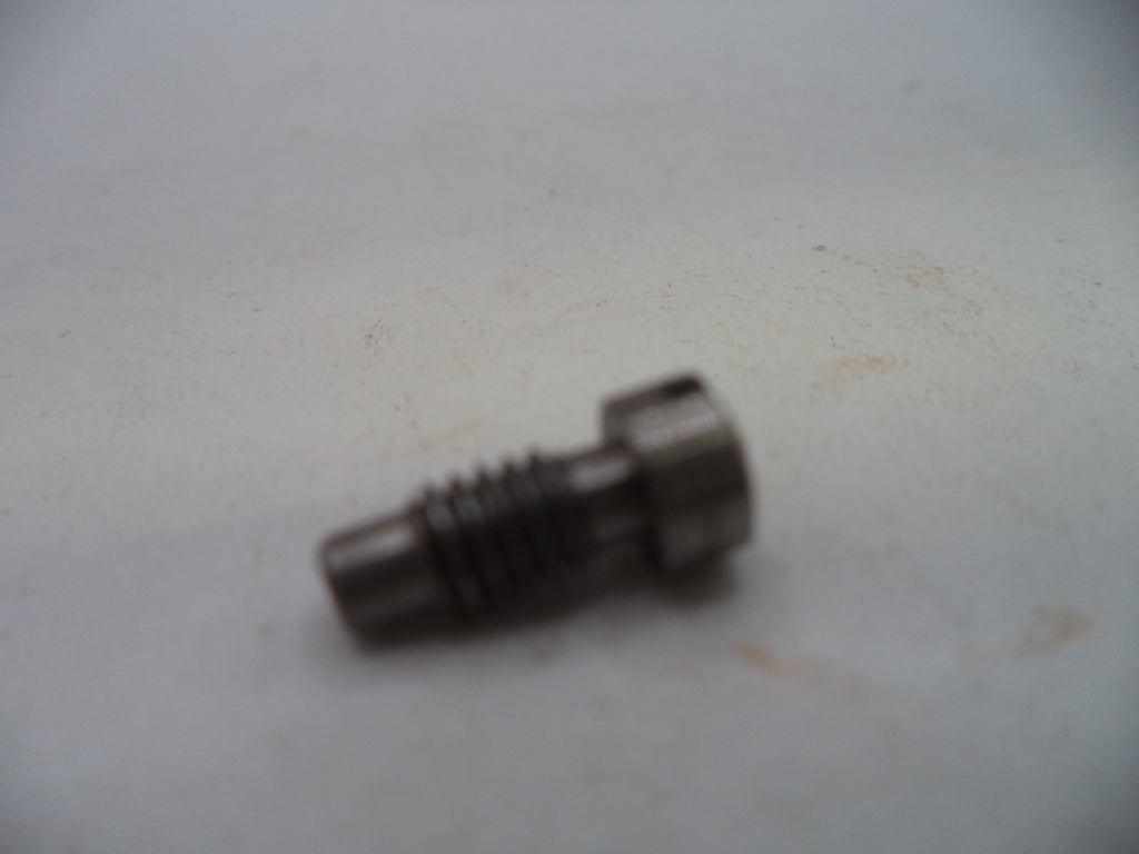 A small metallic threaded component, possibly a bolt or pin, photographed on a plain off-white surface.