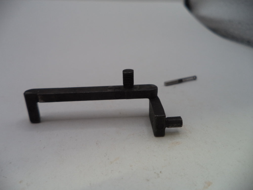A small black metal hardware component with a rectangular bar, angled ends, and a threaded stud, shown on a light gray surface with a small matching screw nearby.