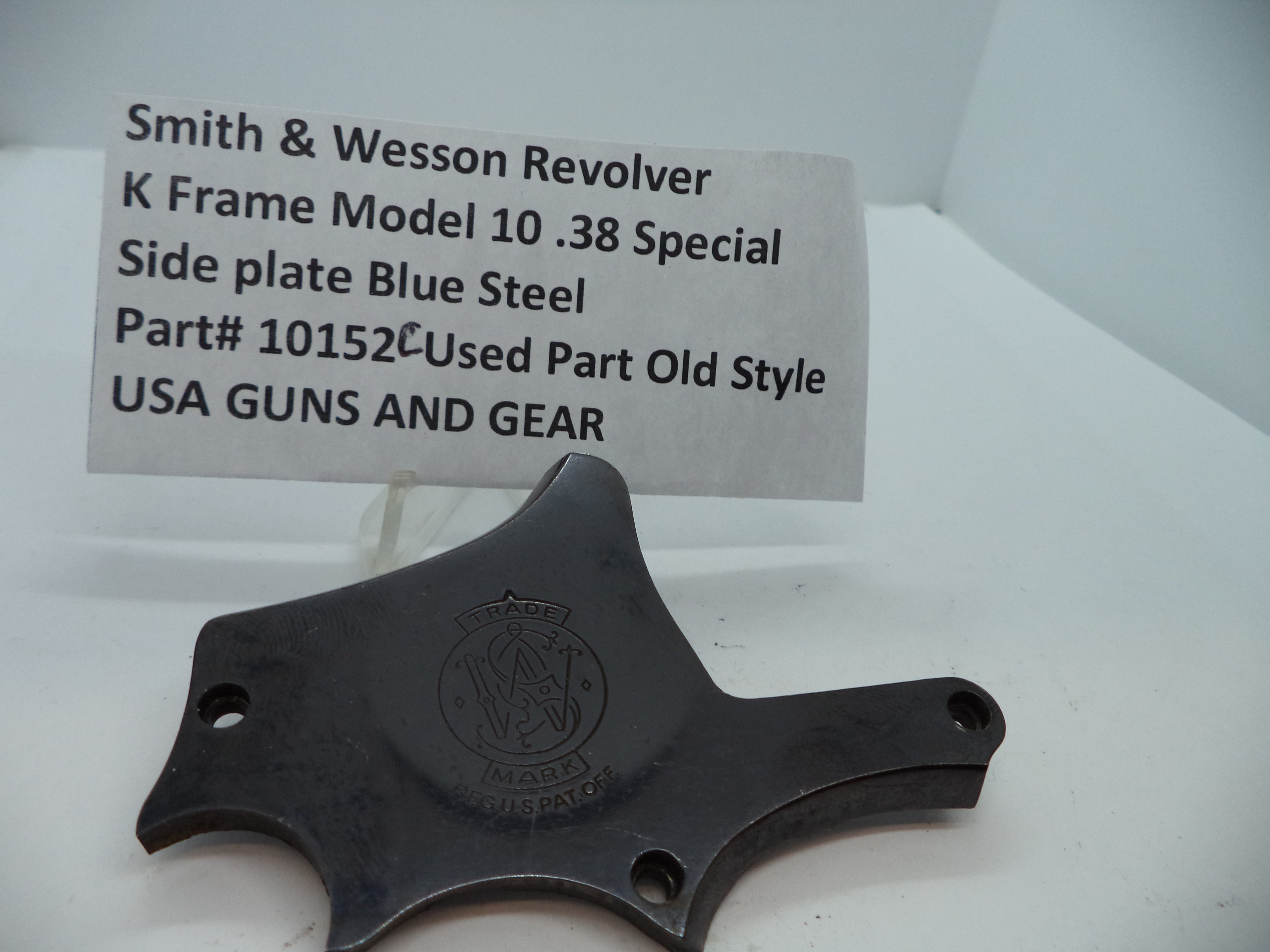 Smith & Wesson K Frame Model 10 Side Plate in blue steel, used as a revolver part, displayed on a white background with a label indicating the model and material.