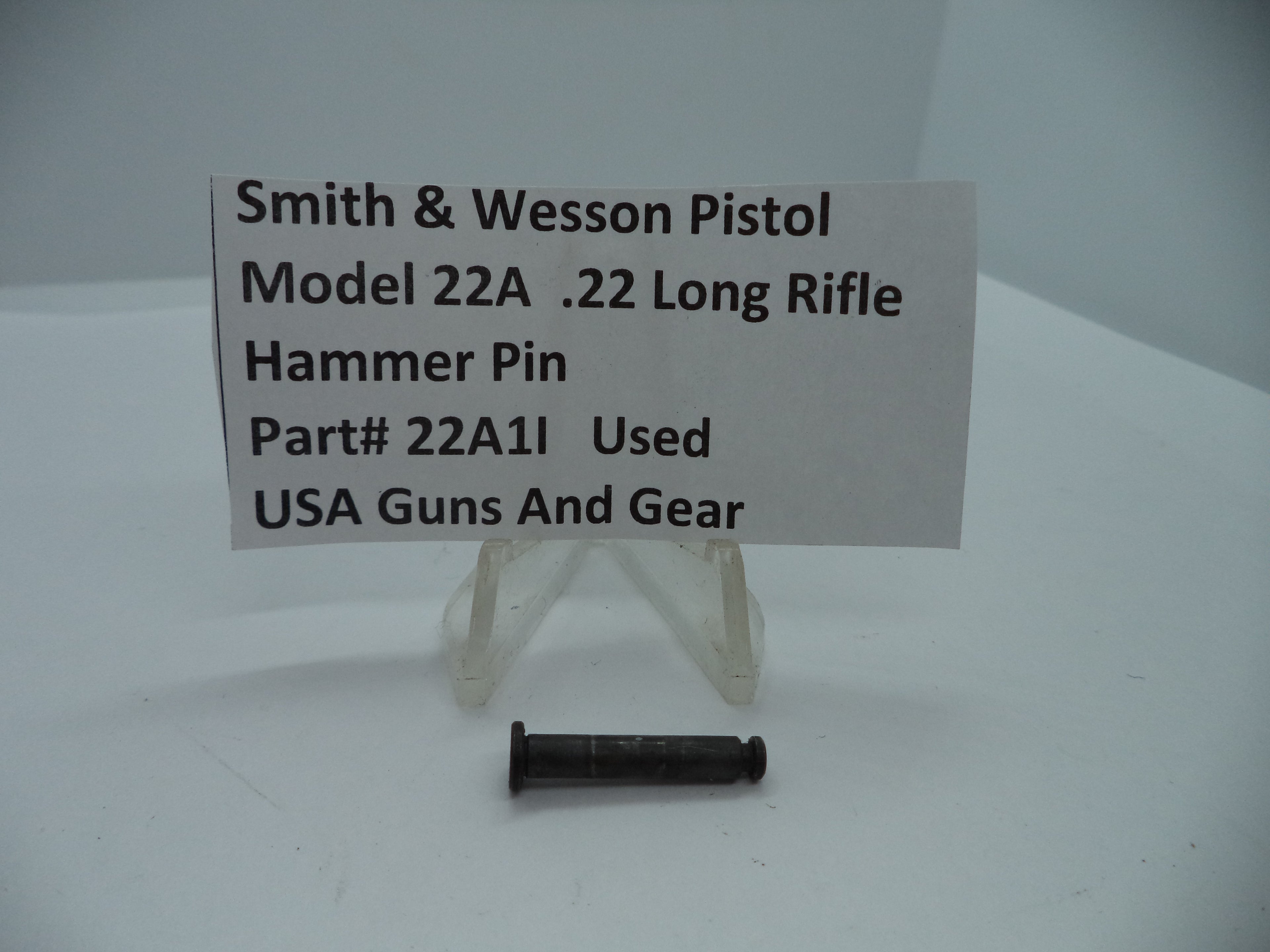 A .22 long rifle hammer pin for a Smith & Wesson Model 22A pistol, displayed on a white card with the product details, indicating it is a used part.