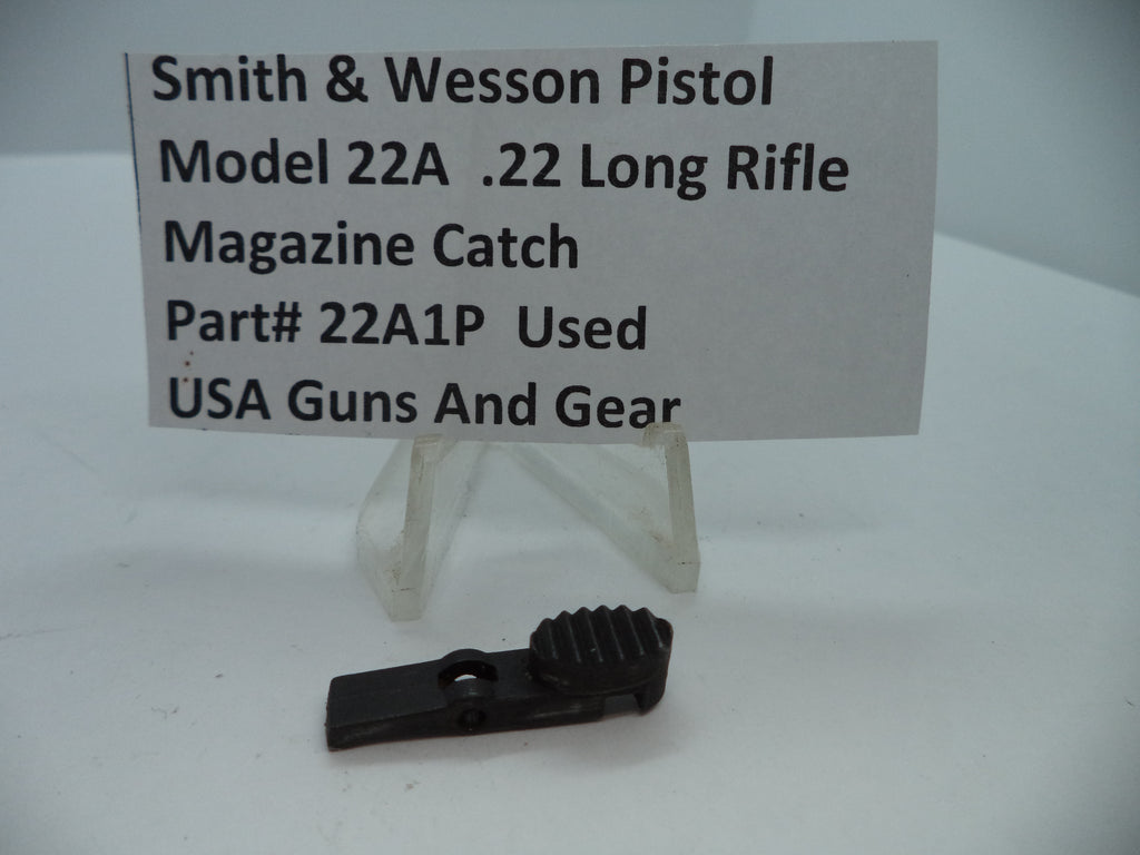 Smith & Wesson Pistol Model 22A Magazine Catch .22 Long Rifle Used Part displayed on a white stand with a label providing product details.