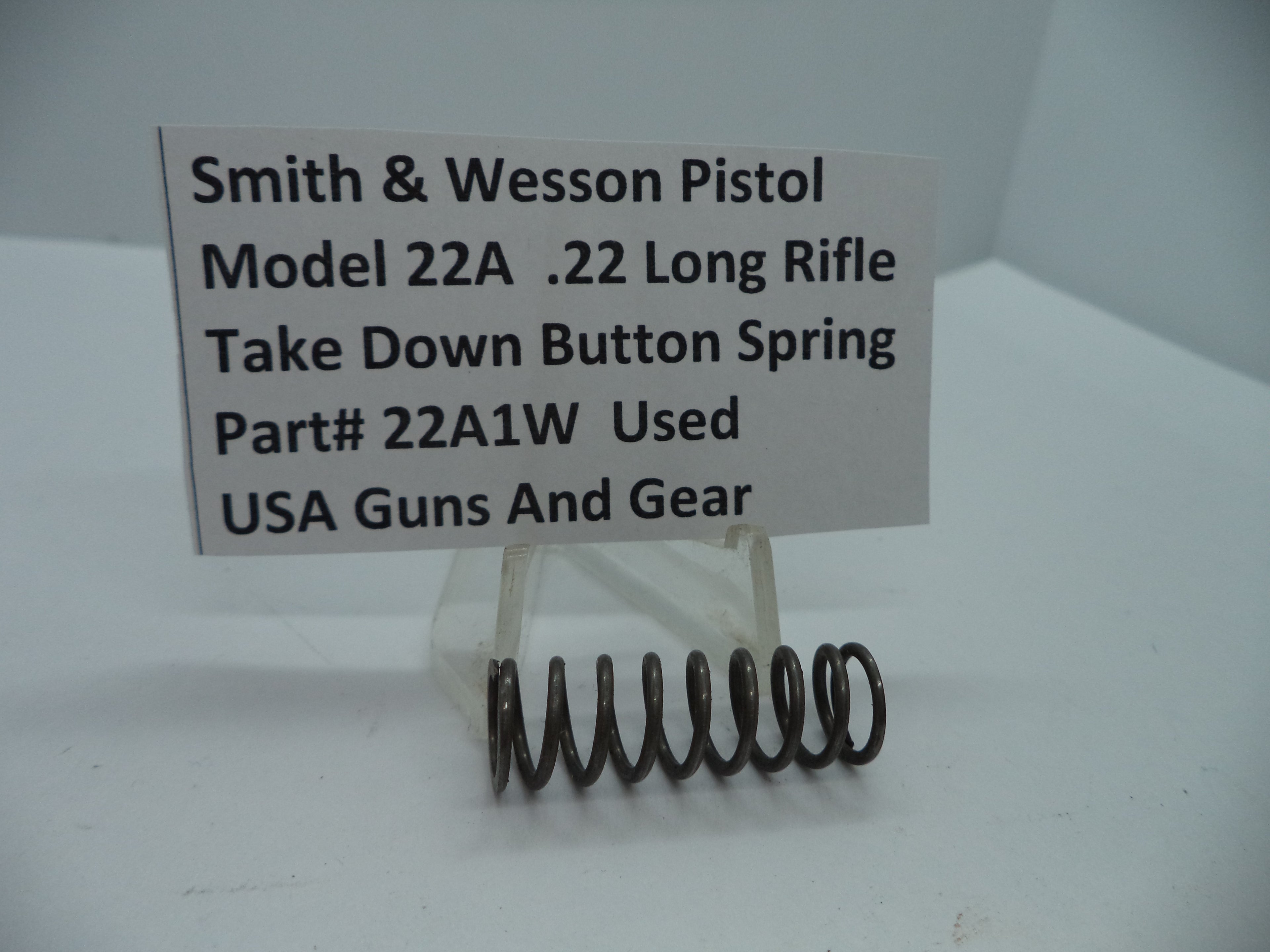 Smith & Wesson Pistol Model 22A Take Down Button Spring for .22 Long Rifle, used part displayed on a white stand with a label.