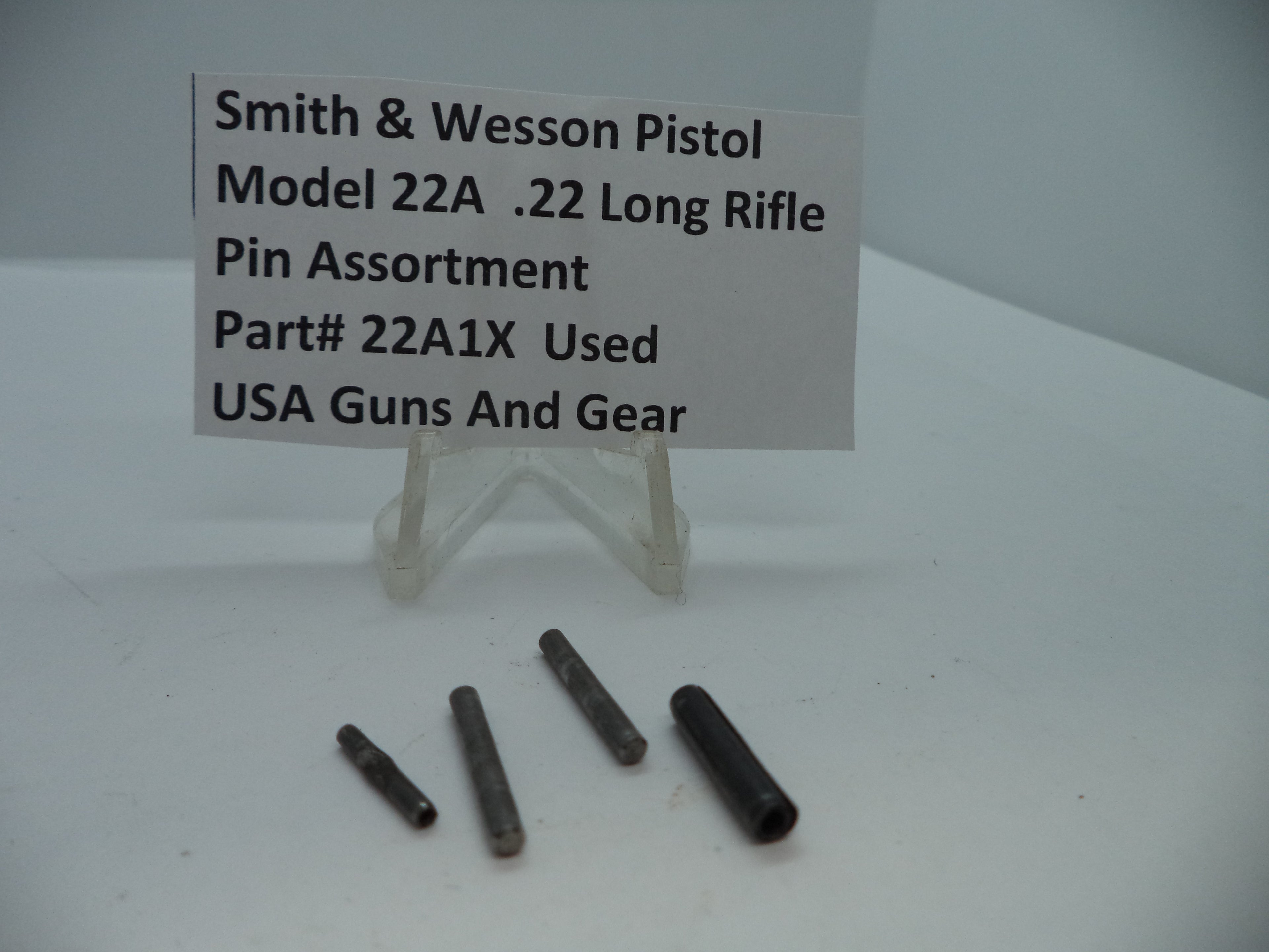 A set of pins for a Smith & Wesson Model 22A .22 Long Rifle pistol displayed on a white stand with a label providing product information.