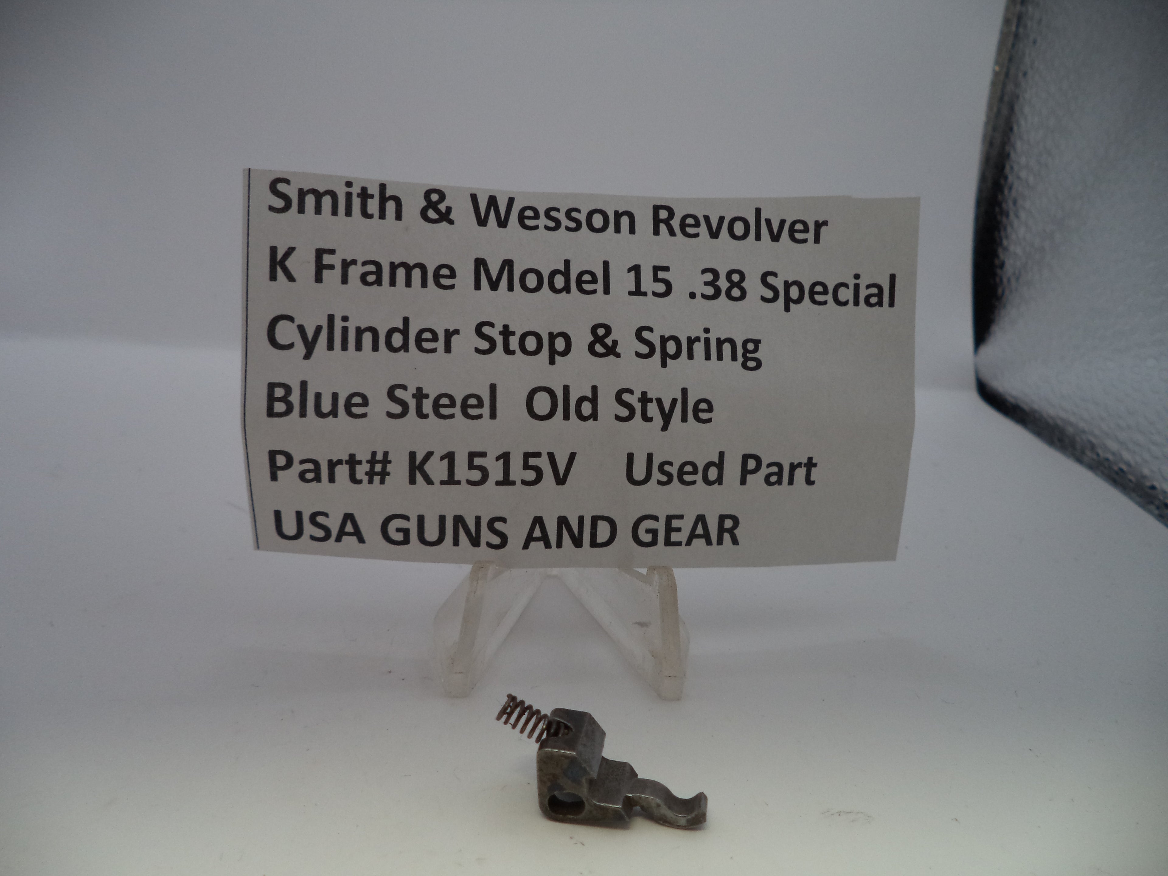 Small metal revolver part on a stand with a label detailing specifications.