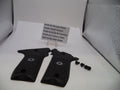 Black pistol grips with screws on a white surface, accompanied by a sign detailing product information.