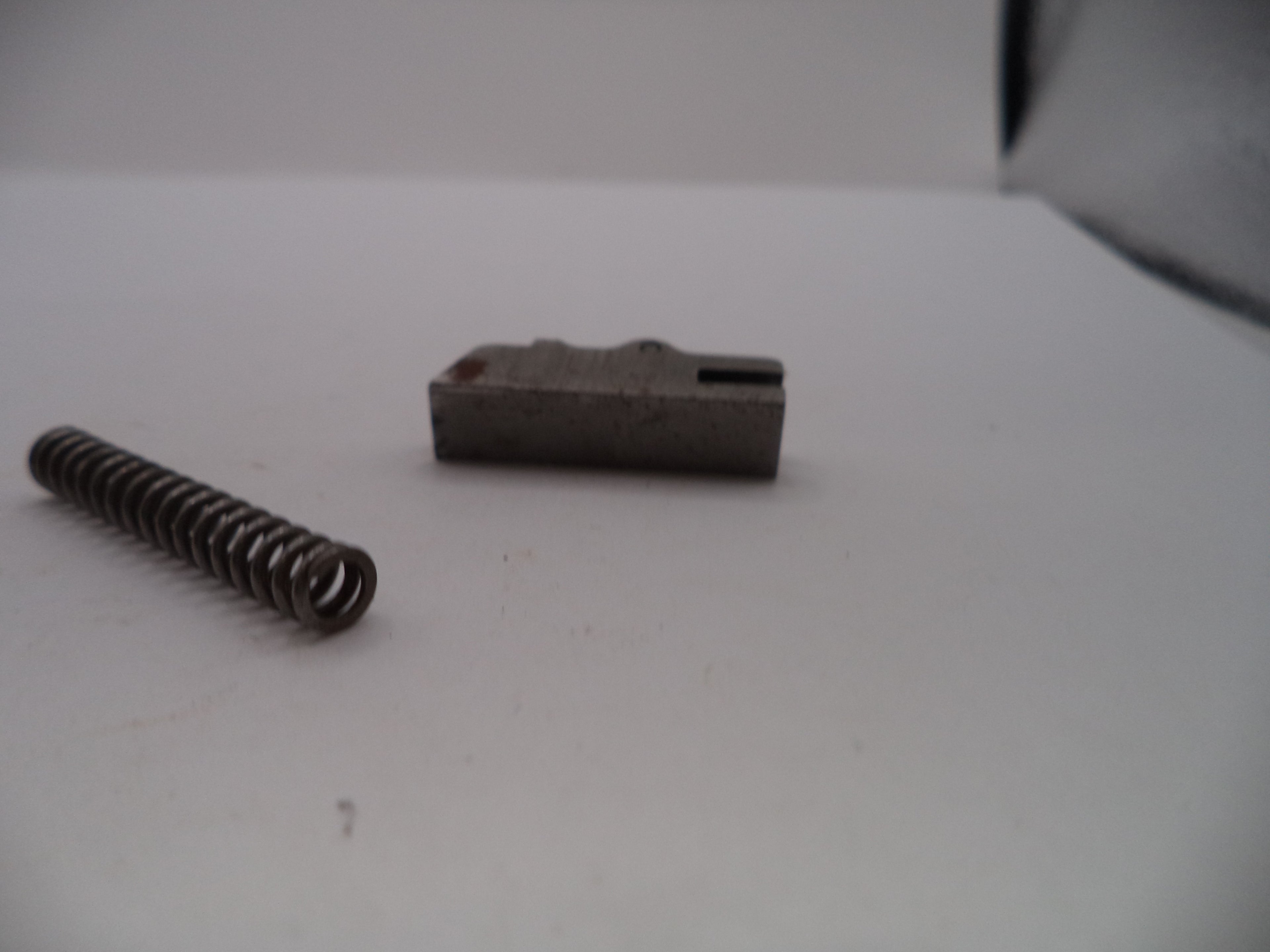 Metal spring and rectangular component on a white surface