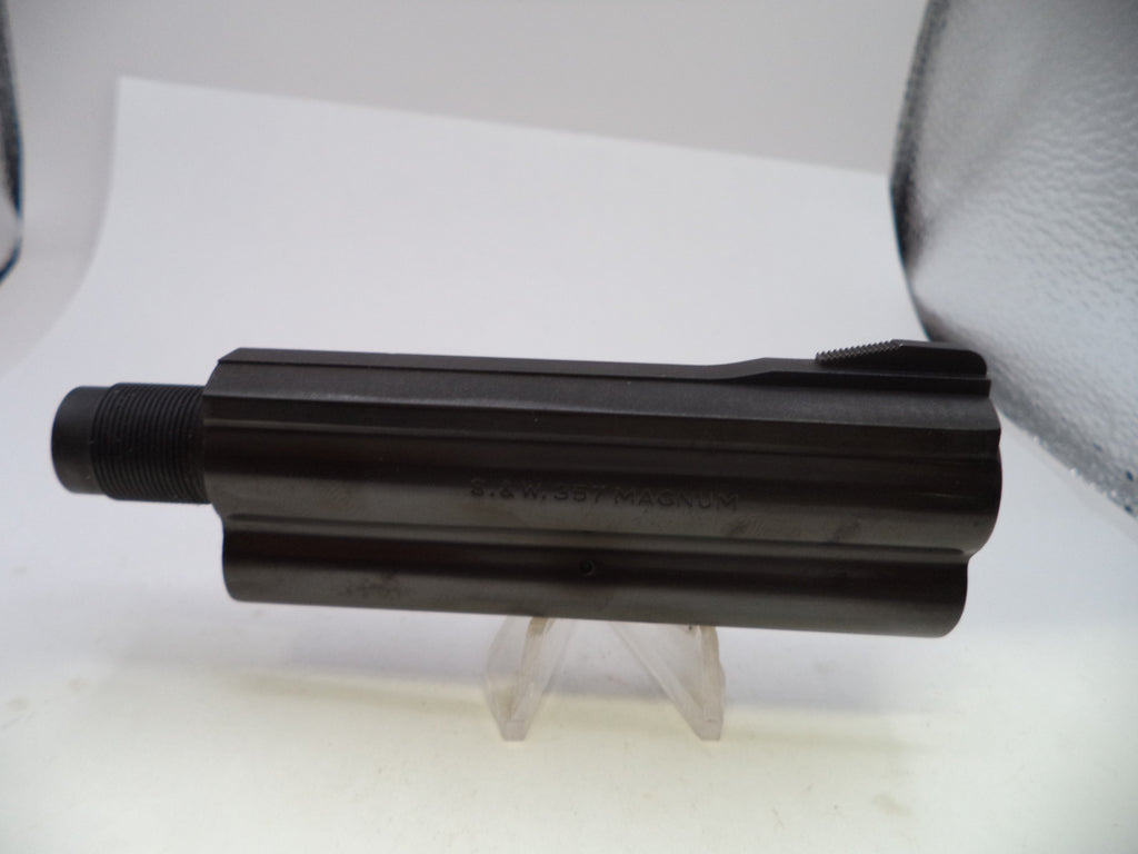 A black metal cylindrical component, likely a firearm magazine or receiver part, displayed on a clear plastic stand against a white background.