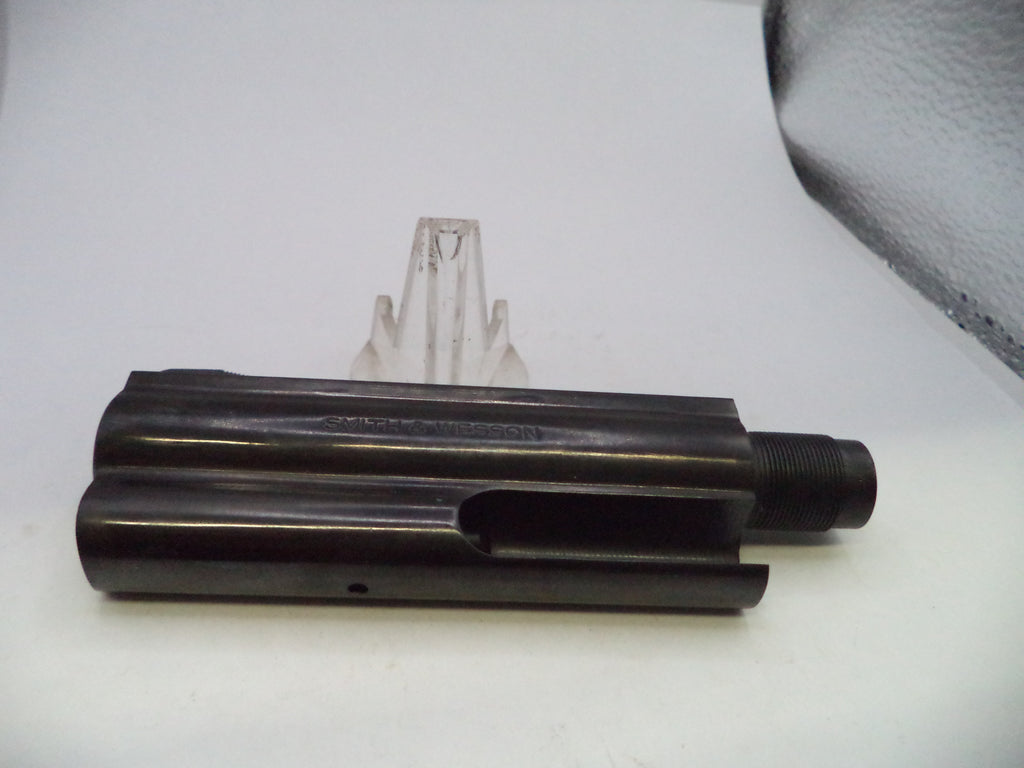 A black metal cylindrical mechanical part with a threaded end, photographed on a white surface with a small clear plastic stand behind it.