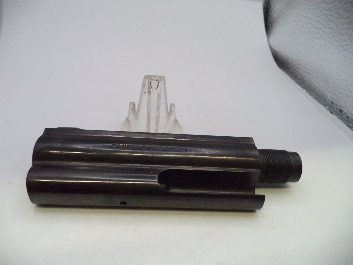 A black metal cylindrical mechanical part with a threaded end, photographed on a white surface with a small clear plastic stand behind it.