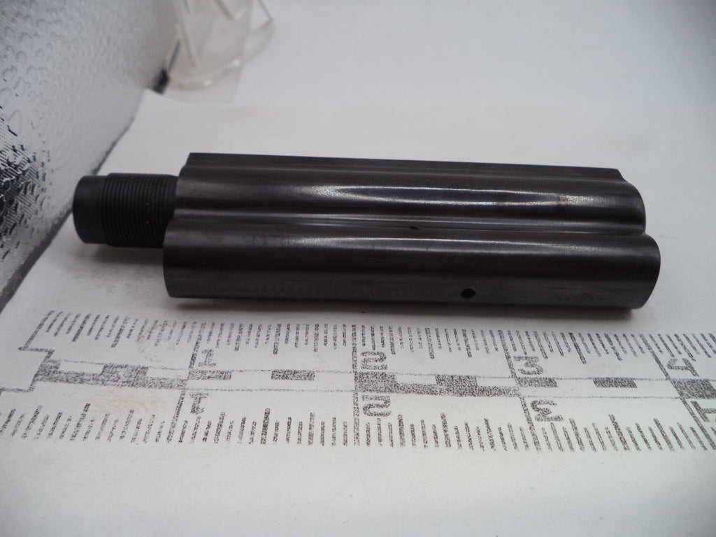 A dark metallic cylindrical mechanical part with a threaded connection on one end, resting on a white paper sheet printed with measurement markings.
