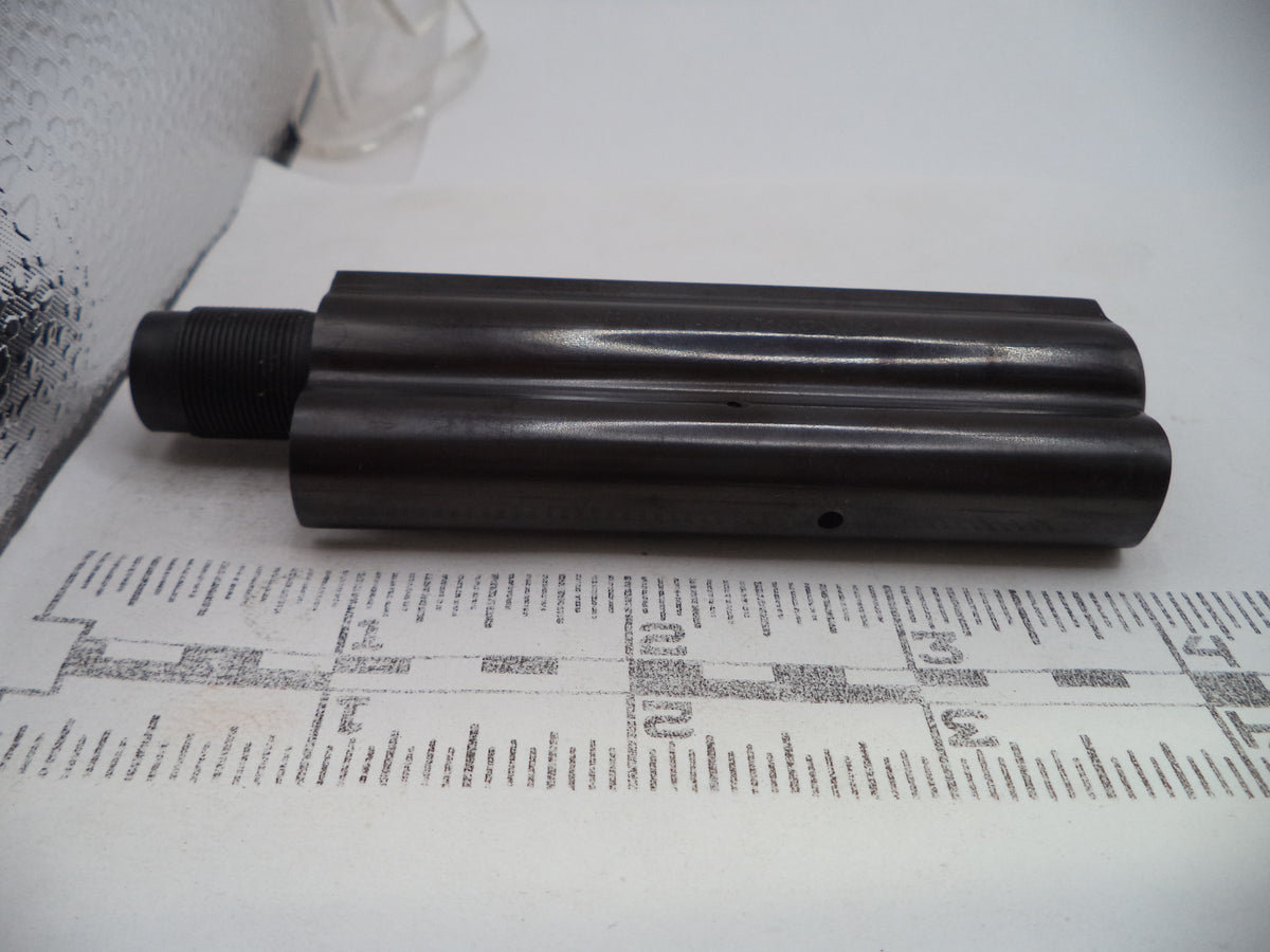A dark metallic cylindrical mechanical part with a threaded connection on one end, resting on a white paper sheet printed with measurement markings.