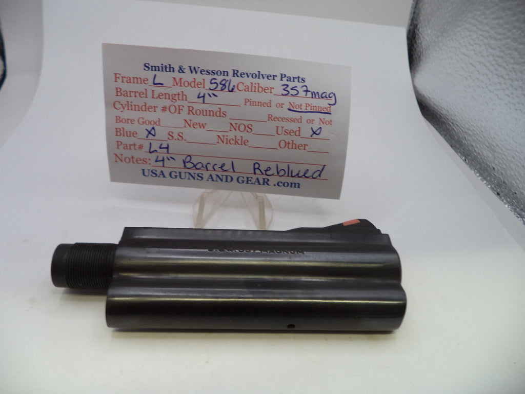 A black metal Smith & Wesson revolver barrel replacement part displayed on a white surface with a handwritten parts information card behind it.