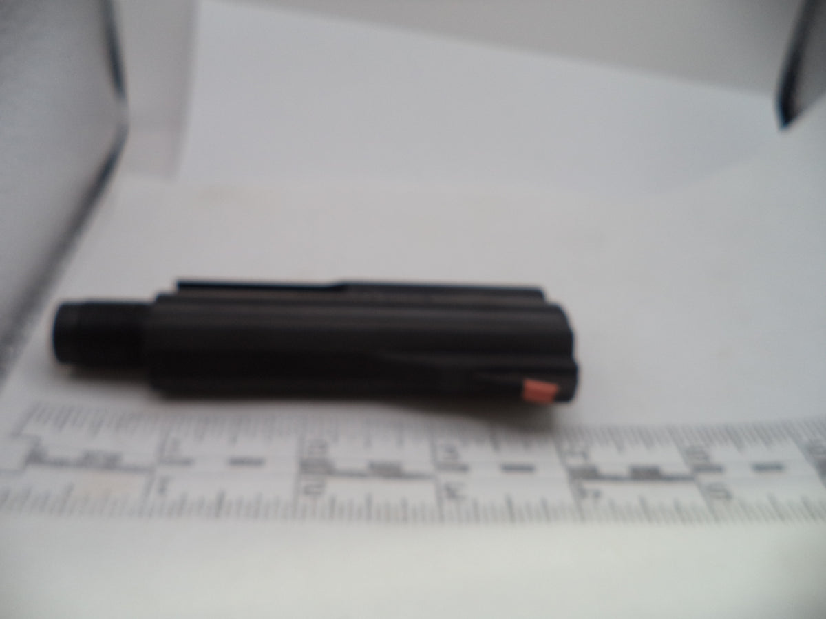 A black cylindrical pen-like tool with a small orange accent, photographed on a white surface next to a ruler for scale.