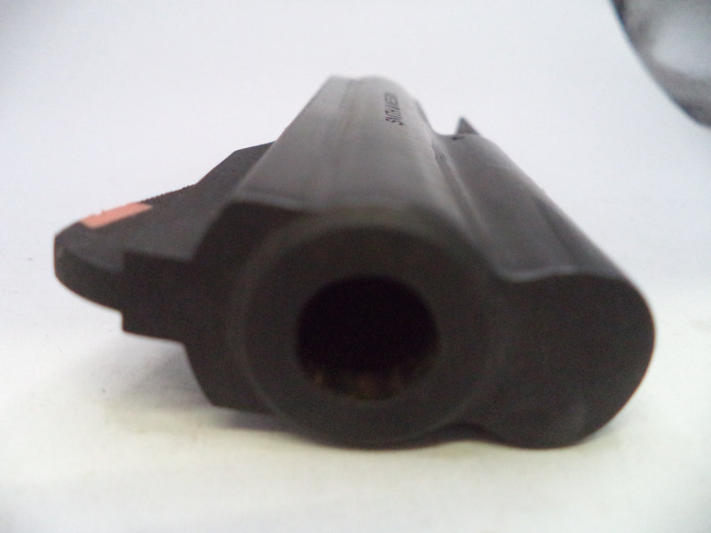 A close-up shot of a black plastic cylindrical component, possibly a barrel or nozzle, with a small orange accent on the side, set against a plain white background.