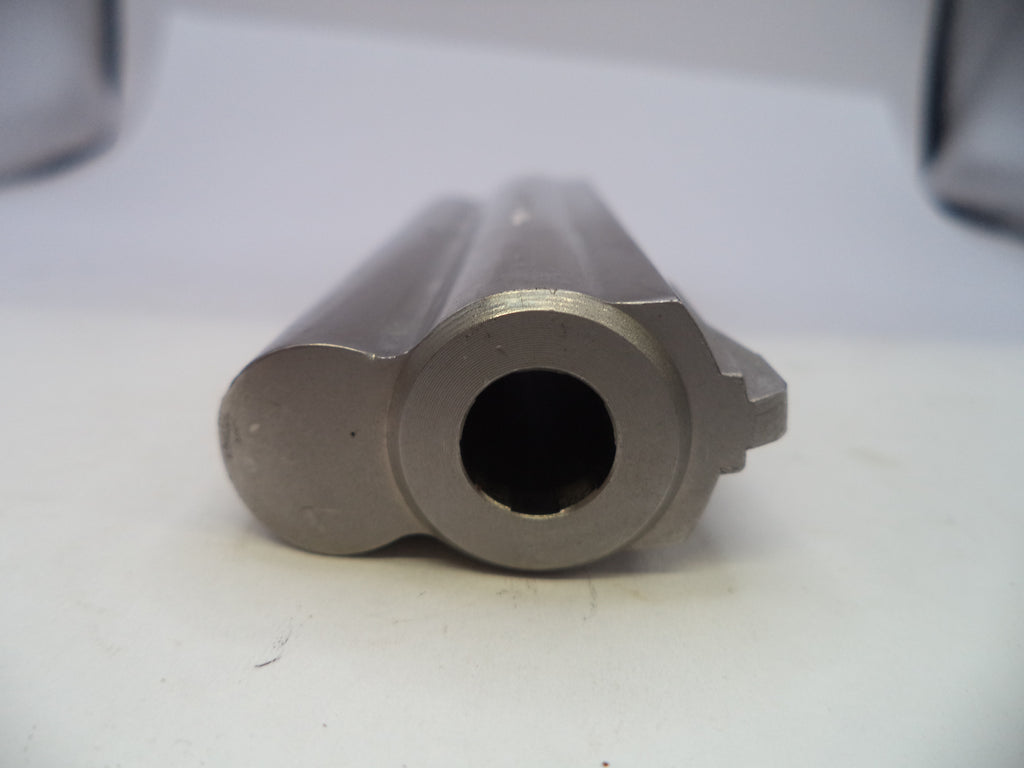 A close-up shot of a metallic gun barrel muzzle, showing the smooth bore and surrounding casing details on a plain white surface.