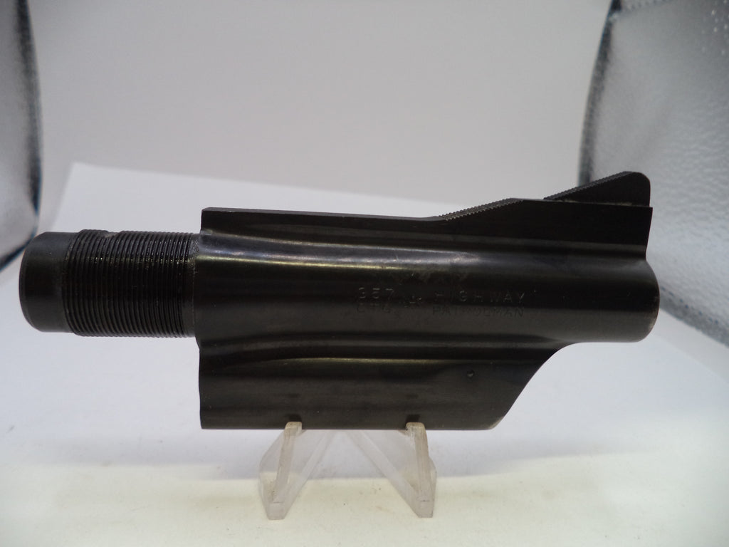 A black metal mechanical component, likely a barrel shroud or receiver part, displayed on a clear plastic stand against a white background.