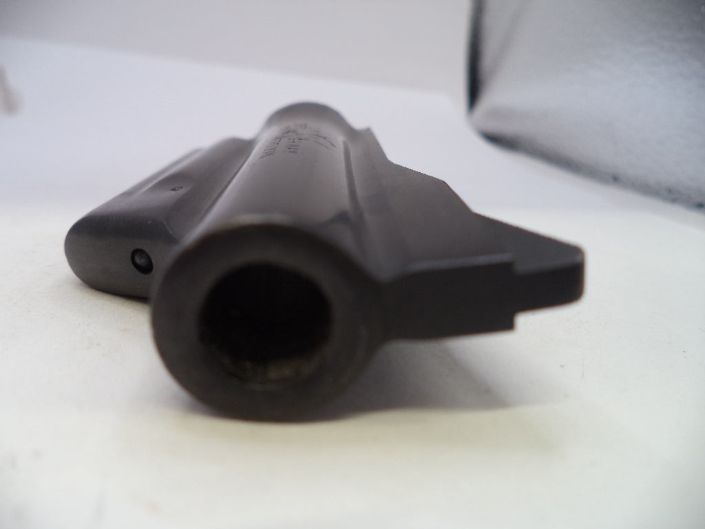 A close-up shot of a black plastic cylindrical component, likely a part of a firearm receiver or grip assembly, resting on a white surface.
