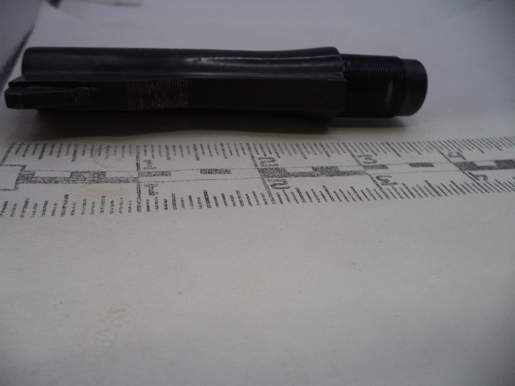 A black cylindrical metal tool or hardware piece placed horizontally on top of a printed ruler against a light background.
