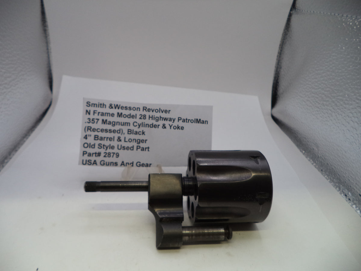 A used black Smith & Wesson revolver cylinder and yoke part, displayed next to its paper label card on a white surface.