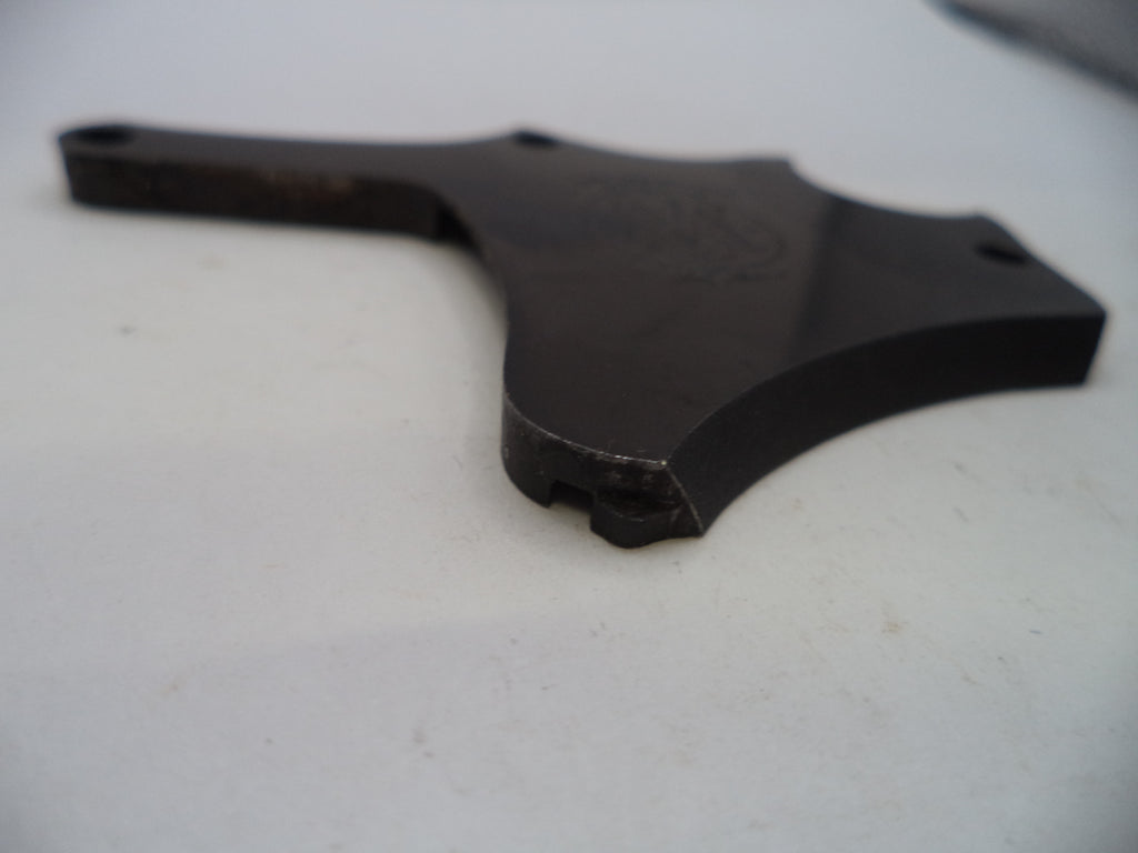 A dark metal mechanical part or bracket with a curved, multi-pronged shape, photographed on a plain off-white surface.