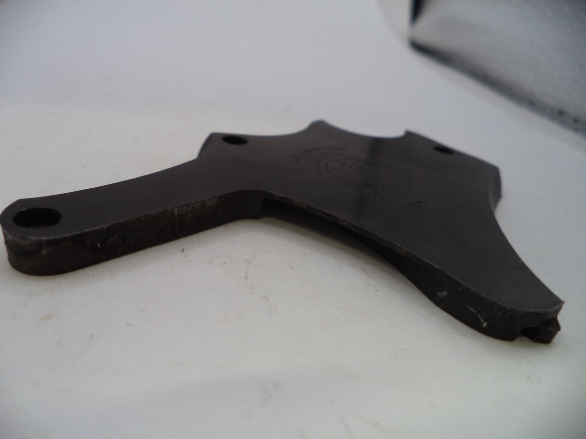 A dark metal mechanical part, likely a bracket or guide, photographed on a white surface.