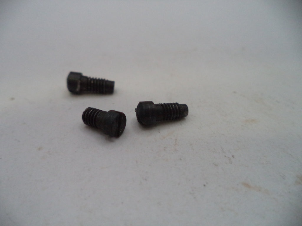 Three small black metal hex head screws on a light gray surface.
