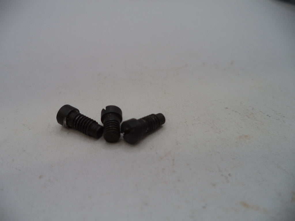 Three small black metal screws with slotted countersunk heads, resting on a light gray surface.