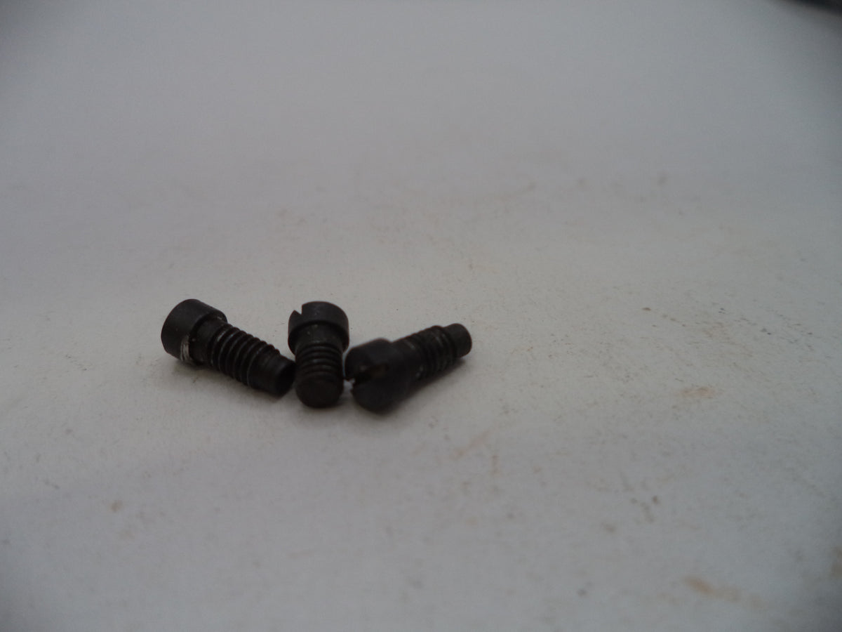 Three small black metal screws with slotted countersunk heads, resting on a light gray surface.
