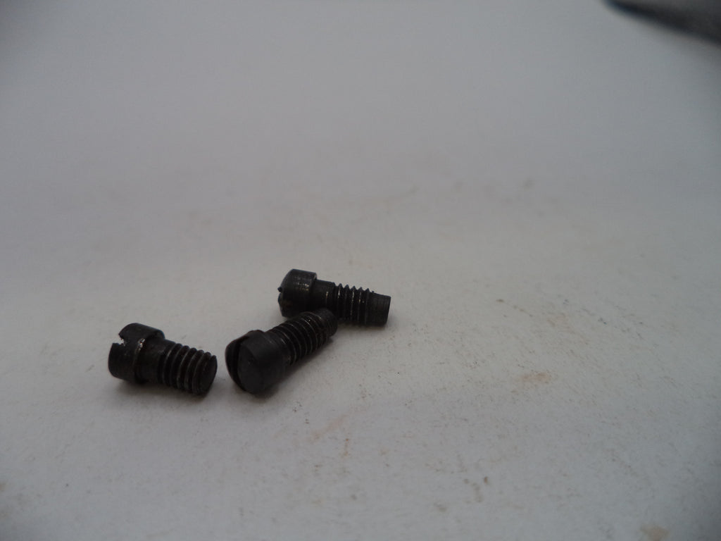 Three small black metal screws with threaded shafts and flat heads, placed on a light gray surface.