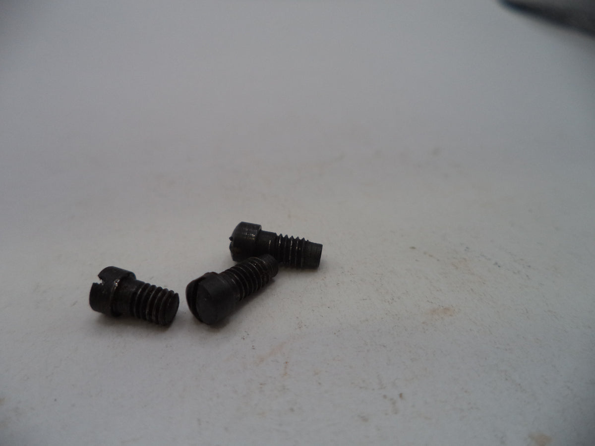 Three small black metal screws with threaded shafts and flat heads, placed on a light gray surface.