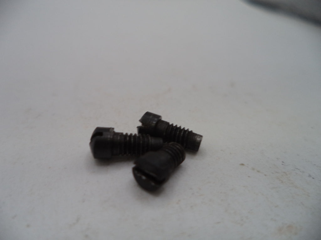 Three small black metal screws with slotted heads, lying on a light off-white surface.