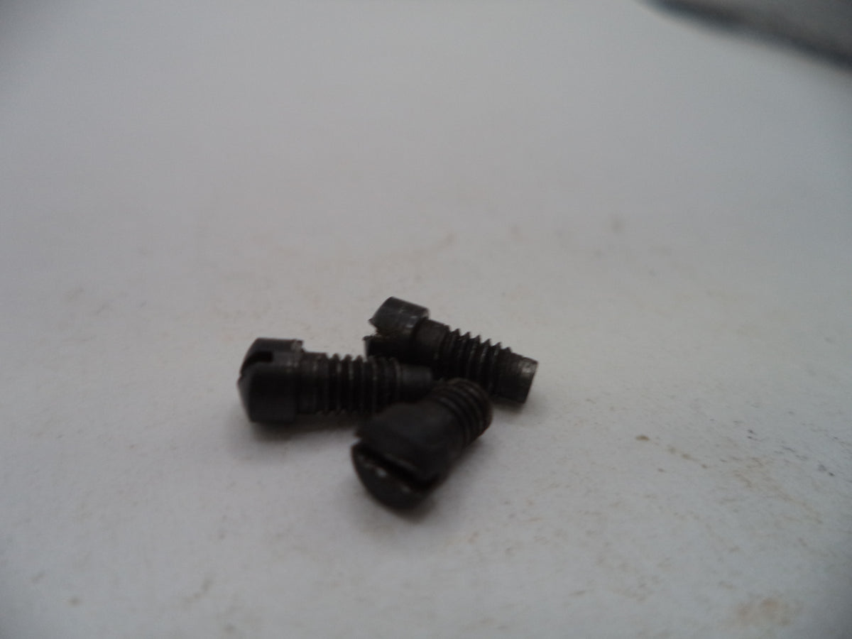 Three small black metal screws with slotted heads, lying on a light off-white surface.