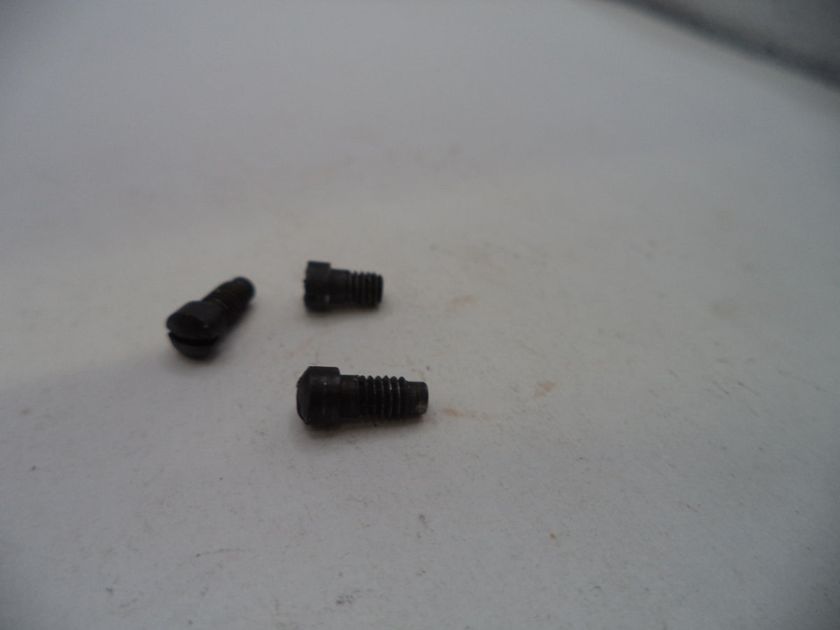 Three small black metal screws or bolts placed on a plain off-white surface.