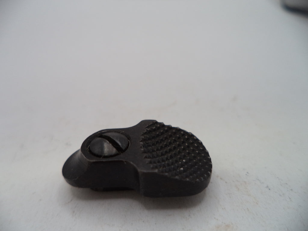 A small black textured metal component with a central screw, photographed on a plain off-white surface.