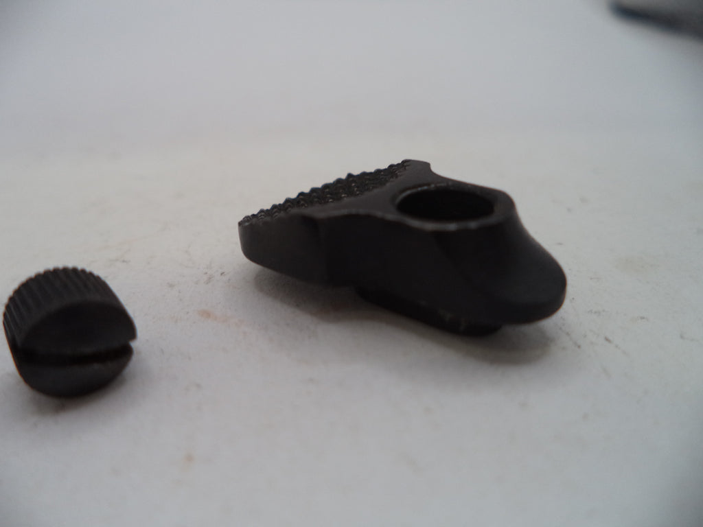 A close-up of a black metal adjustment knob or hardware component with a textured ridged top and a separate matching cap placed beside it on a light gray surface.