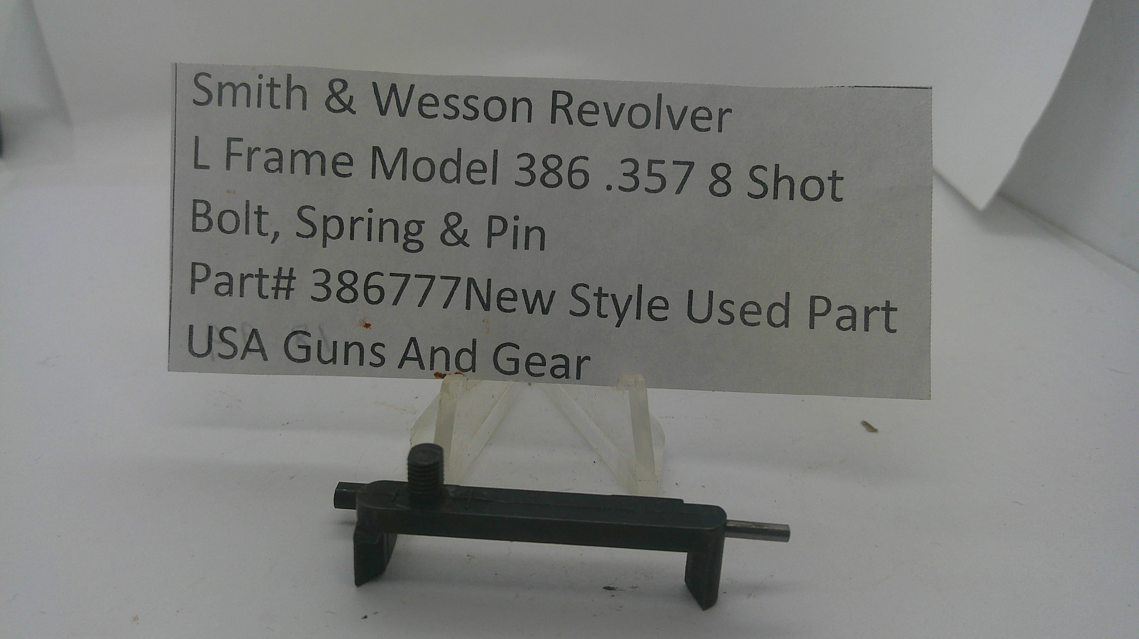 A used black metal Smith & Wesson revolver bolt, spring, and pin part, displayed on a small clear stand with a paper label card behind it on a white background.