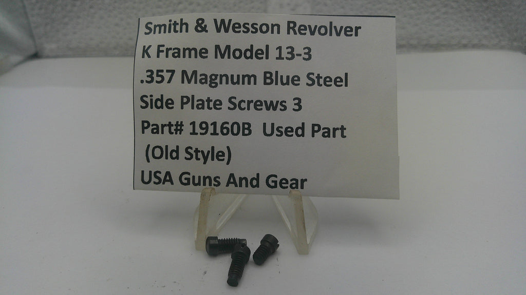 Three small black metal screws displayed in front of a white sign that reads 'Smith & Wesson Revolver K Frame Model 13-3 .357 Magnum Blue Steel Side Plate Screws 3 Part# 19160B Used Part (Old Style) USA Guns And Gear' on a small clear stand.