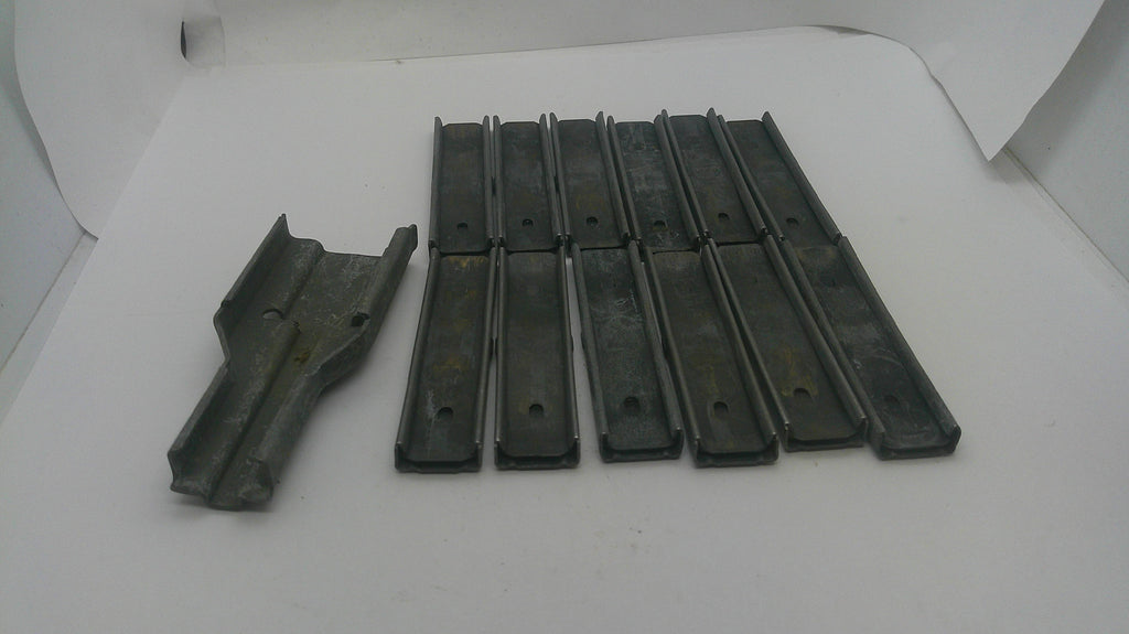 A set of dark gray metal or plastic replacement parts, including one larger piece on the left and several long narrow strips on the right, displayed on a white background.