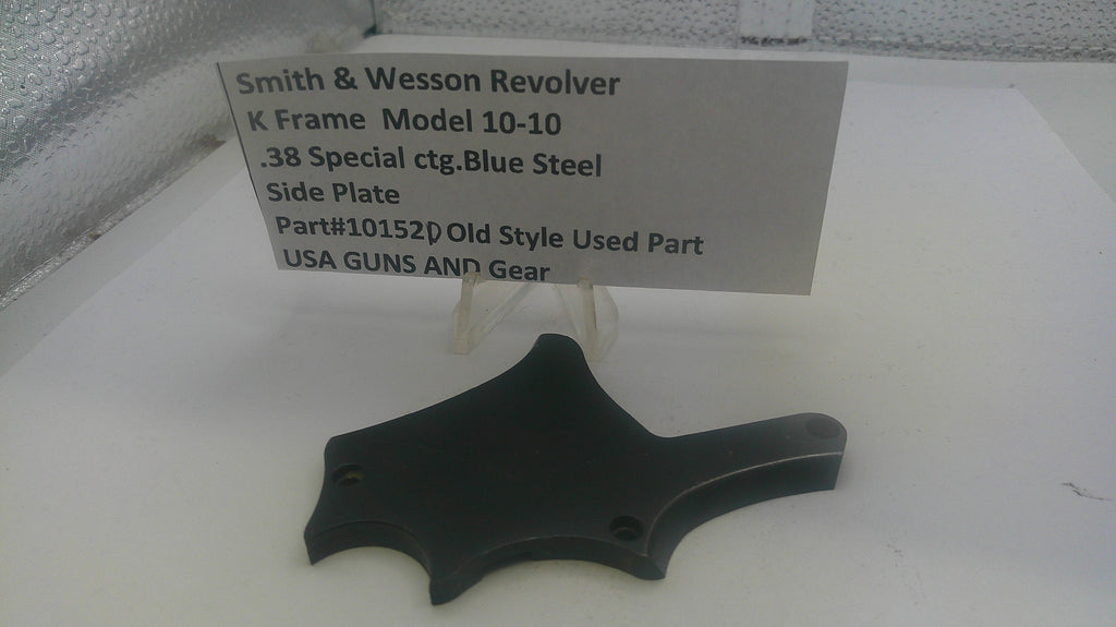 Black side plate for a Smith & Wesson revolver on a white surface with a label.