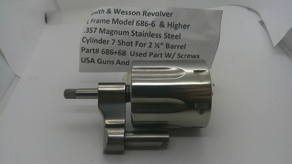 A used metallic revolver cylinder and frame component with a paper tag showing part details, photographed on a white background.